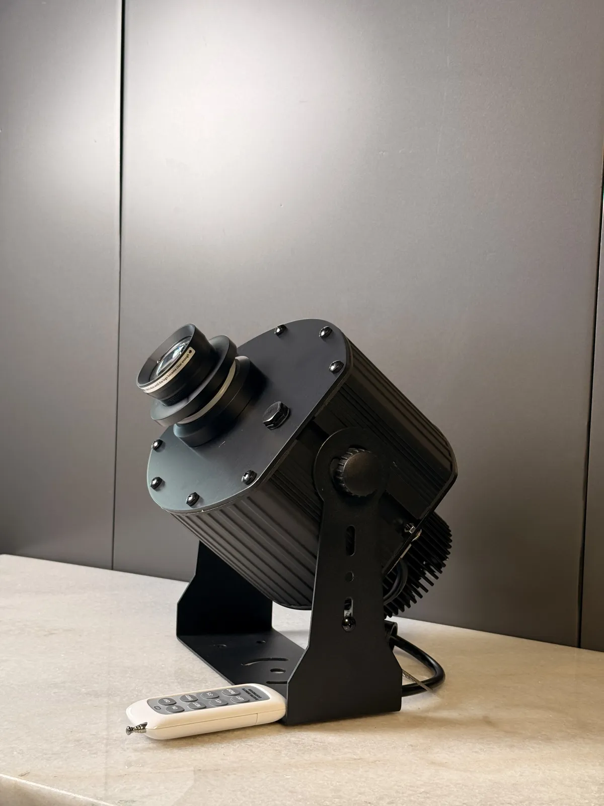 Projecteur gobo LED Megalight MG-X50W / MG-X100W vu de profil avec sa télécommande